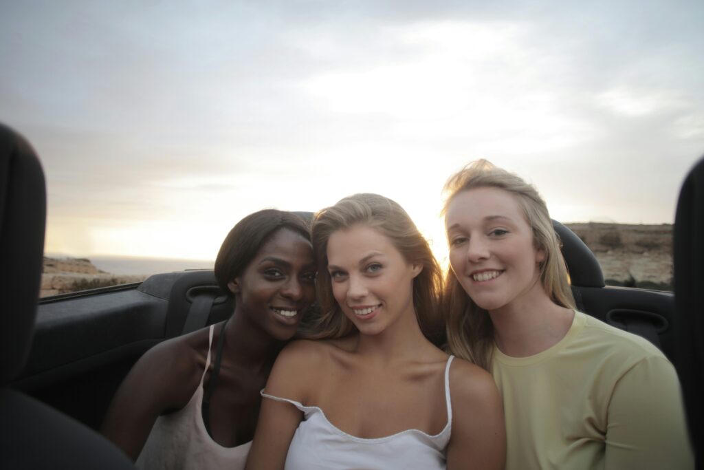 3 women smiling sitting at the back of the car