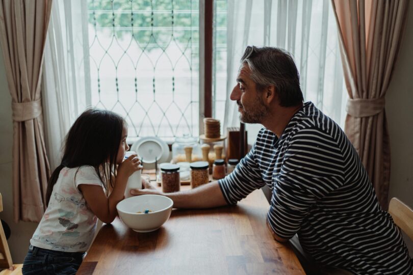 Father and daughter at kitchen table with a breakfast bowl