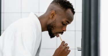 A man in bath robe brushing his teeth