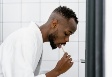 A man in bath robe brushing his teeth