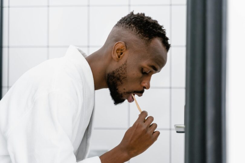 A man in bath robe brushing his teeth