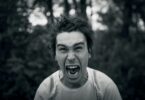 Black and white photo of a man shouting while looking at the camera