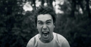 Black and white photo of a man shouting while looking at the camera