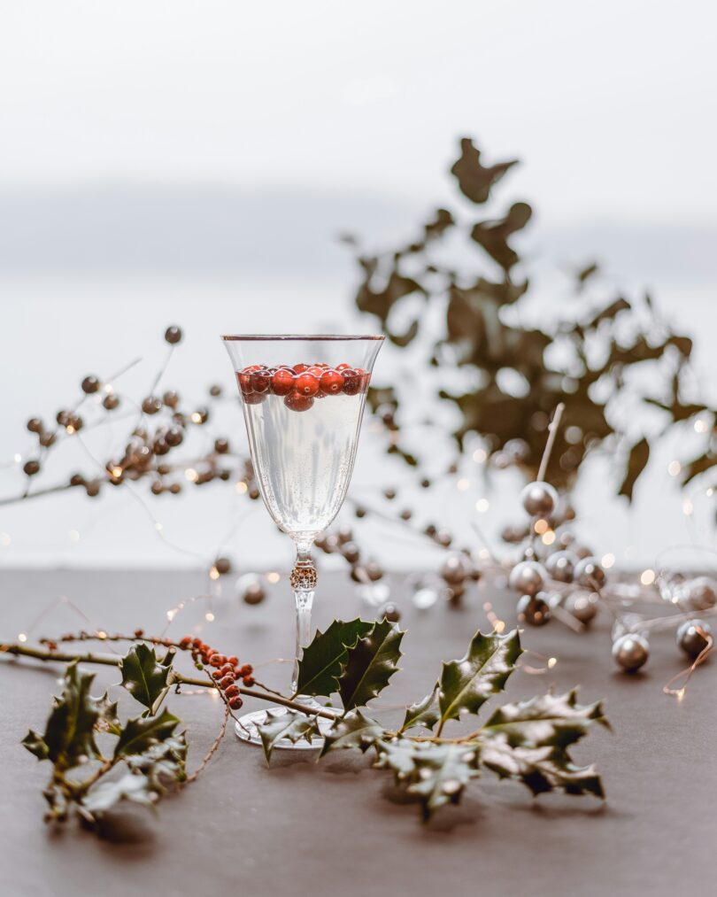 A Festive Holiday Cocktail in a Tall Glass with Holly and Decorations