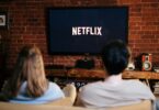 Man and woman sitting on a couch in front of a television