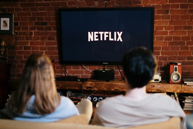 Man and woman sitting on a couch in front of a television