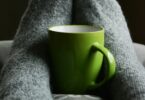 Green ceramic mug on person s feet