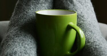 Green ceramic mug on person s feet