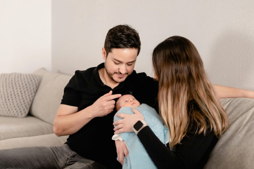 Woman sitting on sofa while carrying an infant